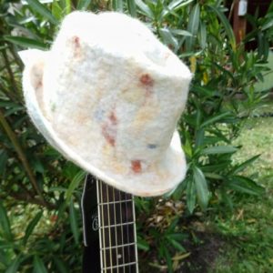trilby blanc tacheté couleur posé sur le manche de la guitare